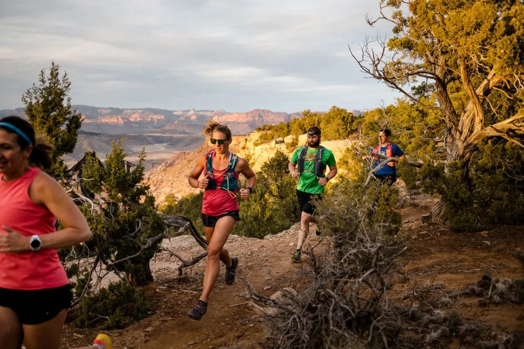 Vacation Races Zion at Night group of runners sprinting next to a cliff