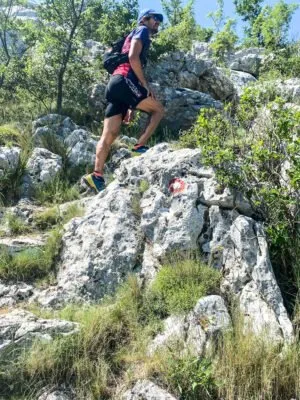 A runner trekking up a stone cliffside