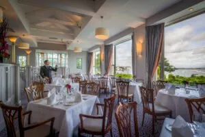a fine hotel dining room with large windows and formal place settings